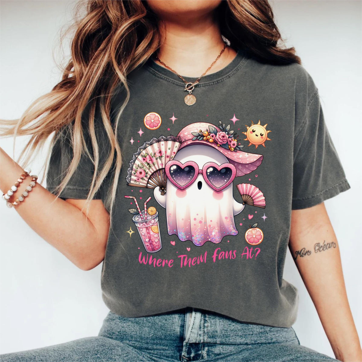 May include: Dark gray t-shirt featuring a cartoon ghost wearing heart-shaped sunglasses, a floral hat, and holding a fan. The ghost is holding a drink and the text "Where Them Fans At?" is below the ghost.