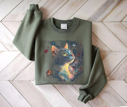May include: Olive green sweatshirt featuring a vibrant graphic of a cat with a cosmic design. The cat's fur is depicted with a galaxy of colors, including blues, oranges, and yellows, set against a dark background. The cat is looking upwards.