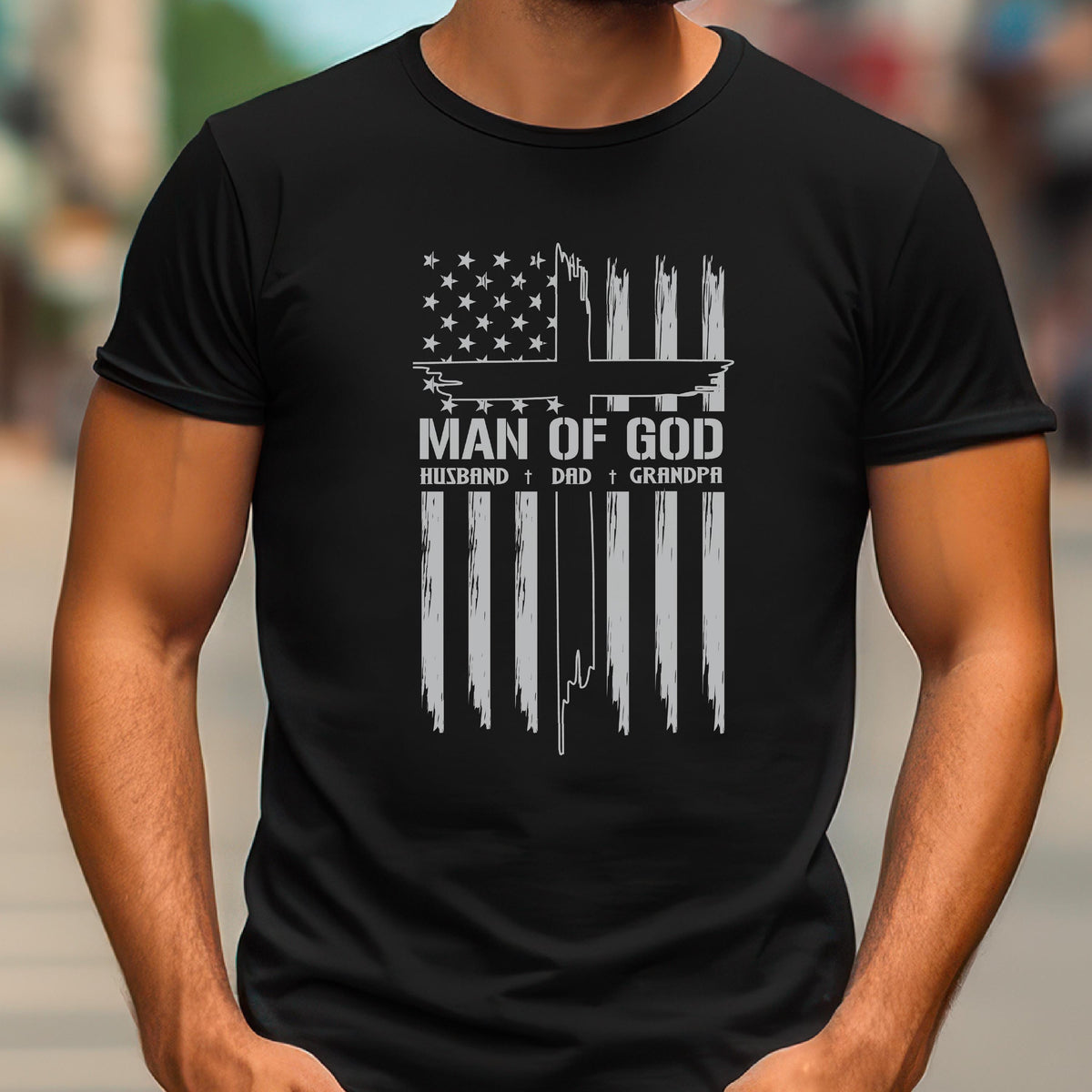 May include: Black t-shirt featuring a distressed American flag design with a cross and the words "MAN OF GOD, HUSBAND, DAD, GRANDPA" in white. The shirt has a crew neck and short sleeves.