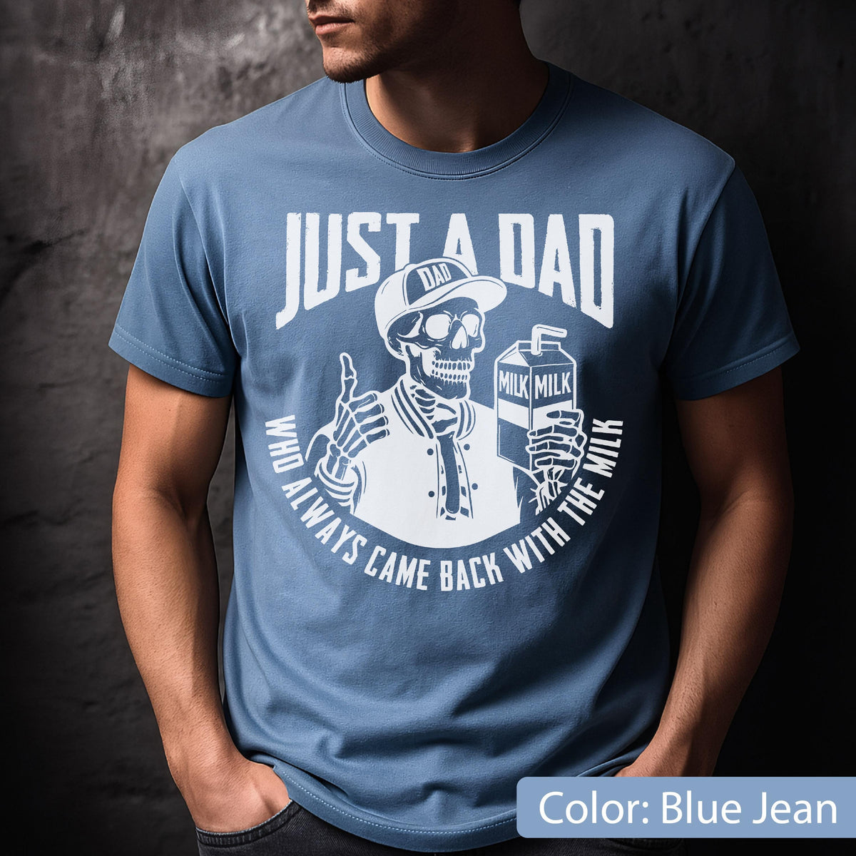 May include: Blue jean t-shirt with a white graphic. The graphic features a skeleton wearing a baseball cap and jacket, holding a milk carton. Text reads "JUST A DAD WHO ALWAYS CAME BACK WITH THE MILK."