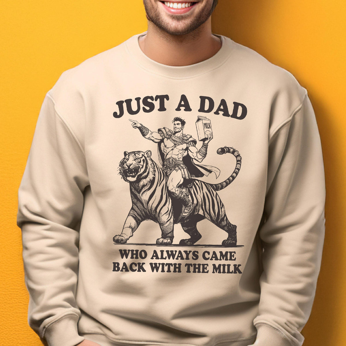 May include: Beige sweatshirt with a graphic of a superhero riding a tiger, holding a milk carton. Text reads "JUST A DAD WHO ALWAYS CAME BACK WITH THE MILK" in black. The design is a humorous take on fatherhood.