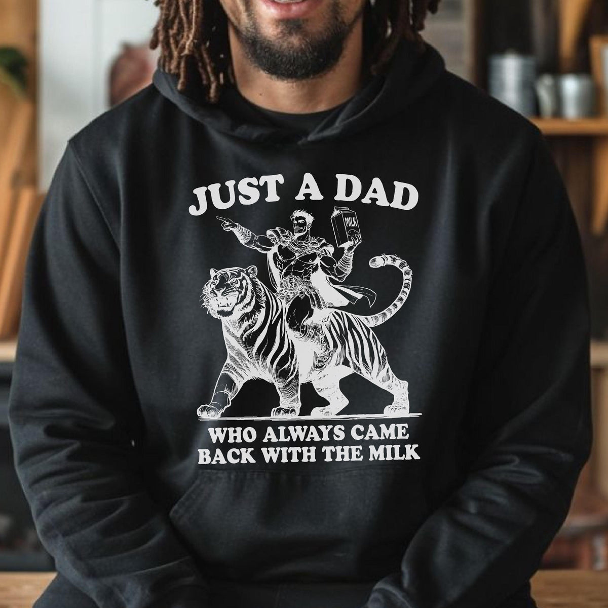 May include: Black hoodie with a white graphic of a man riding a tiger, holding a milk carton. The text reads "JUST A DAD WHO ALWAYS CAME BACK WITH THE MILK."