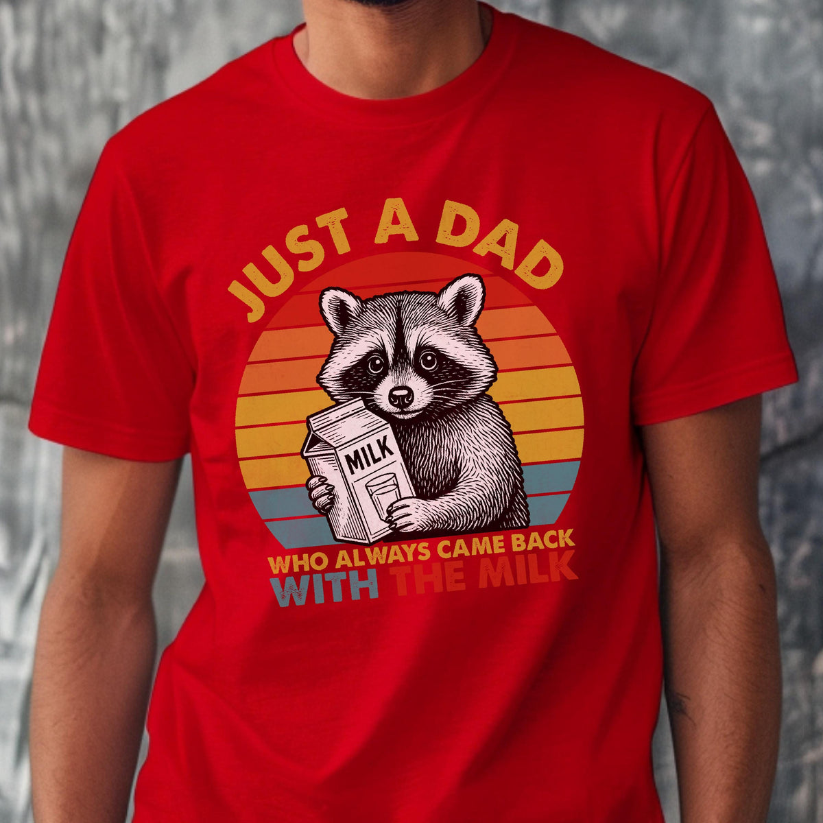 May include: Red t-shirt featuring a raccoon holding a milk carton, set against a retro sunset design. Text reads "JUST A DAD WHO ALWAYS CAME BACK WITH THE MILK" in yellow and white. A humorous graphic tee.