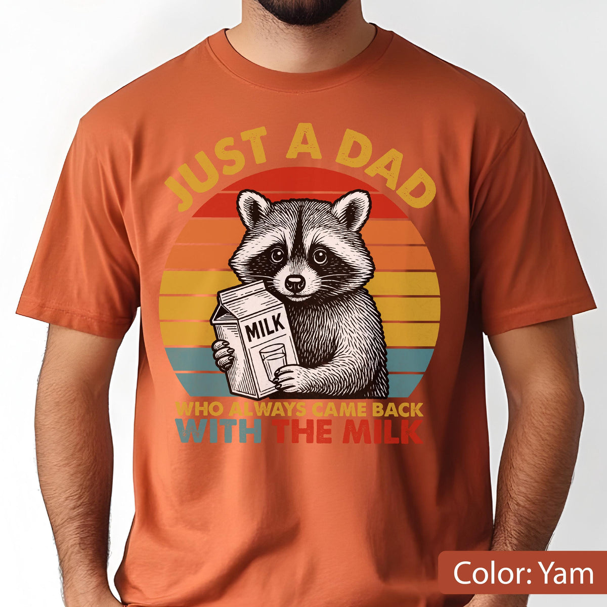 May include: Yam-colored t-shirt featuring a raccoon holding a milk carton. The design includes a sunset background and the text "JUST A DAD WHO ALWAYS CAME BACK WITH THE MILK."