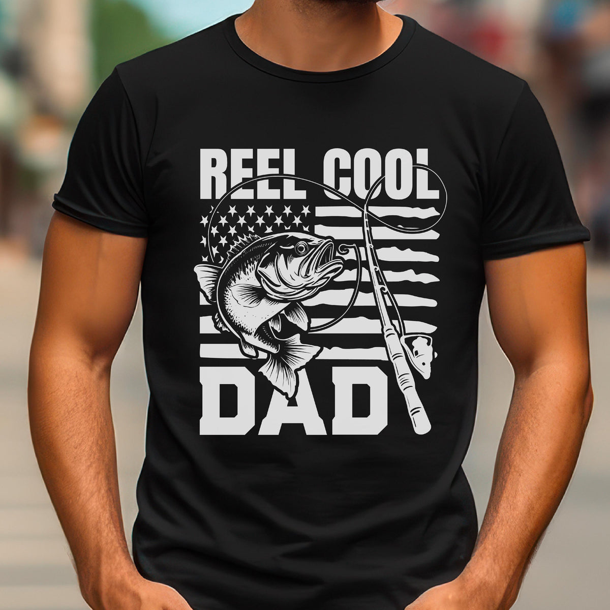 May include: Black t-shirt with a white graphic featuring a fish, fishing rod, and the words "REEL COOL DAD." The design incorporates the American flag. A great gift for fishing enthusiasts.