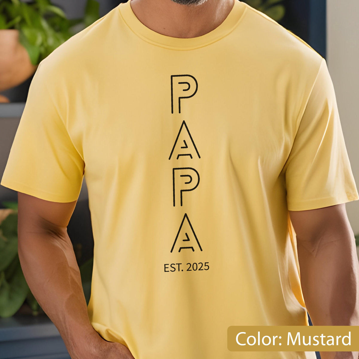 May include: Mustard yellow t-shirt with the word "PAPA" in black, vertical block letters. Below the word "PAPA" is the text "EST. 2025". The shirt has short sleeves and a crew neck.