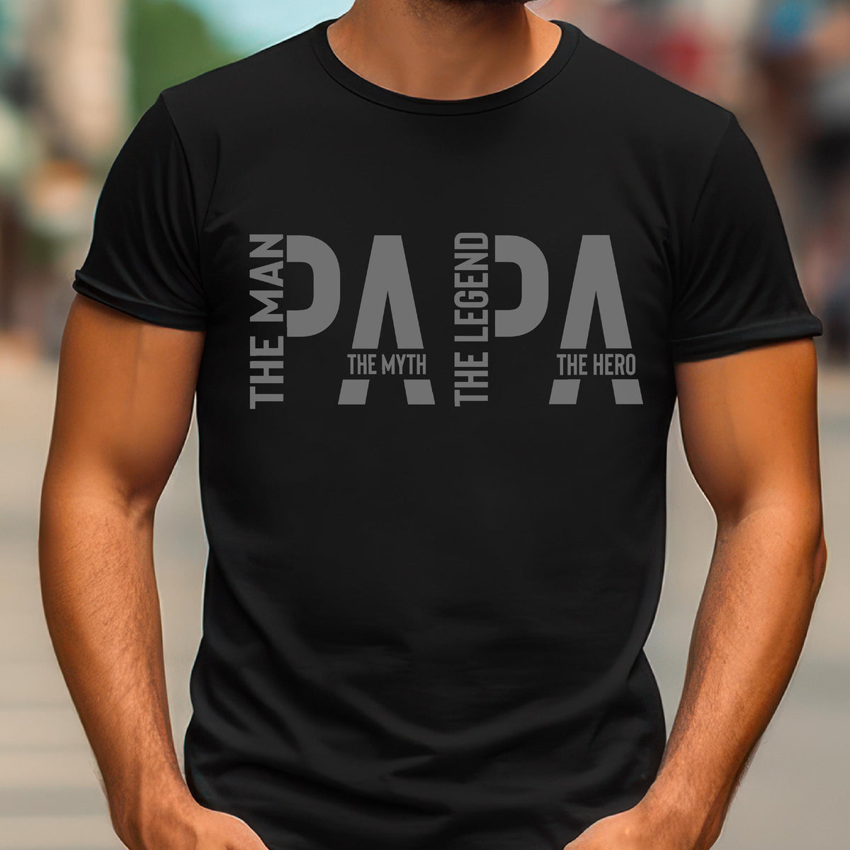 May include: Black t-shirt with the word "PAPA" in gray block letters. The text is accompanied by the phrases "The Man," "The Myth," "The Legend," and "The Hero," arranged vertically on the left and right sides of the word "PAPA."