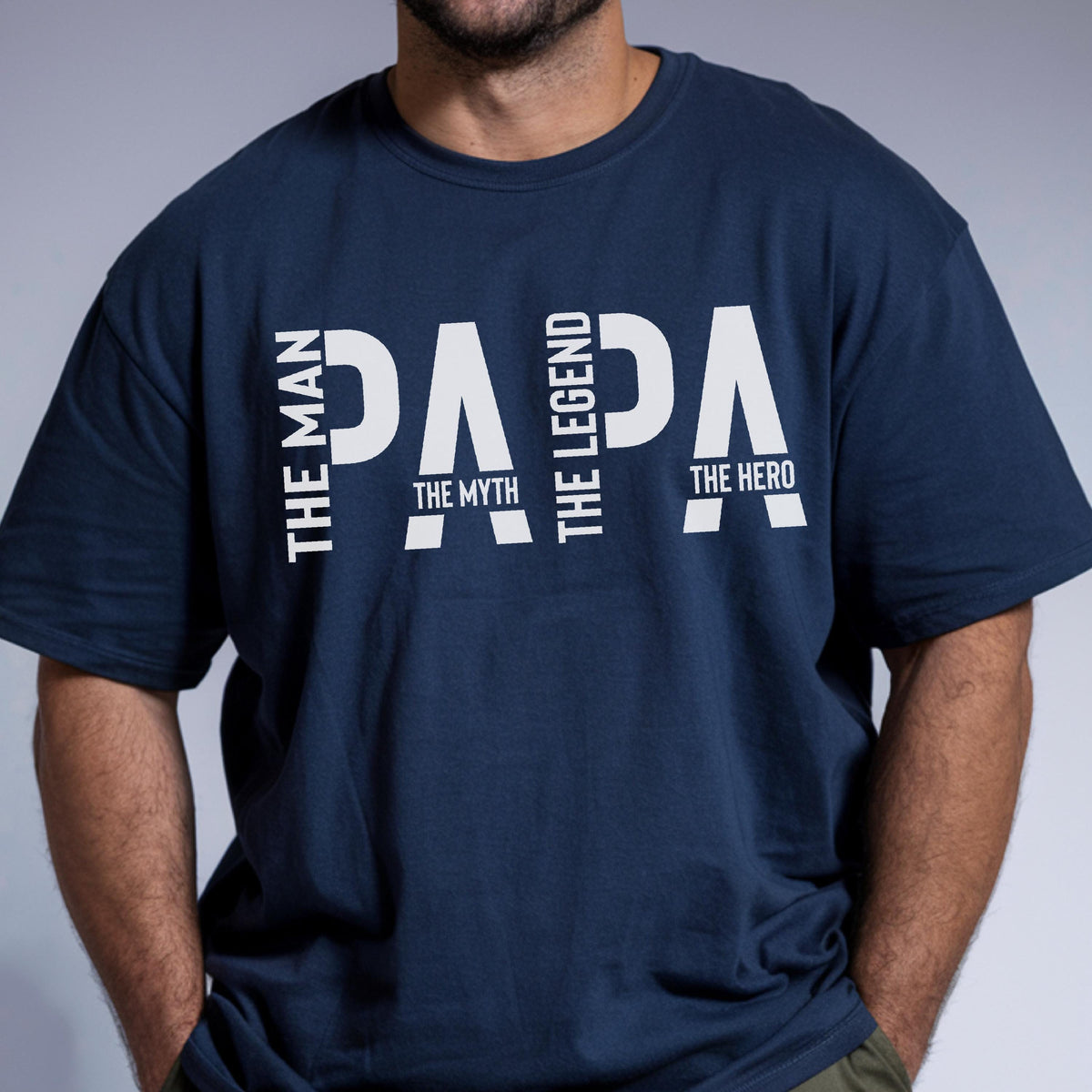May include: Navy blue t-shirt with the word "PAPA" in large white letters. The words "THE MAN", "THE MYTH", "THE LEGEND", and "THE HERO" are printed vertically on the left and right sides of the word "PAPA".