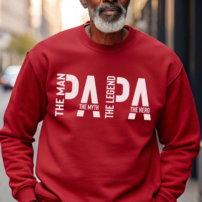 May include: A red sweatshirt with the word "PAPA" in white block letters. The text "THE MAN, THE MYTH, THE LEGEND, THE HERO" is vertically aligned on the left and right sides of the word "PAPA".