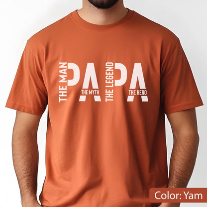May include: A short-sleeved, yam-colored t-shirt with the word "PAPA" in large white capital letters. The words "THE MAN", "THE MYTH", "THE LEGEND", and "THE HERO" are printed vertically on the left and right sides of the word "PAPA".