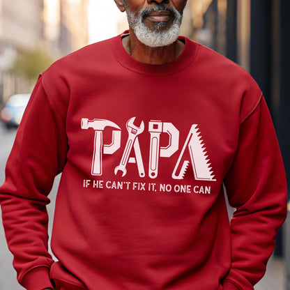 May include: A red sweatshirt with the word "PAPA" in white, stylized with tools. Below the word is the text "IF HE CAN'T FIX IT, NO ONE CAN". The sweatshirt is a crew neck style.