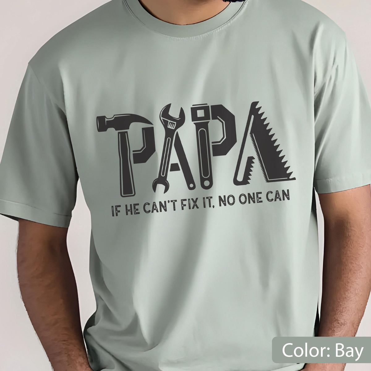 May include: A light green t-shirt with the word "PAPA" spelled out using tools like a hammer, wrench, and saw. The text "IF HE CAN'T FIX IT, NO ONE CAN" is printed below the word "PAPA".