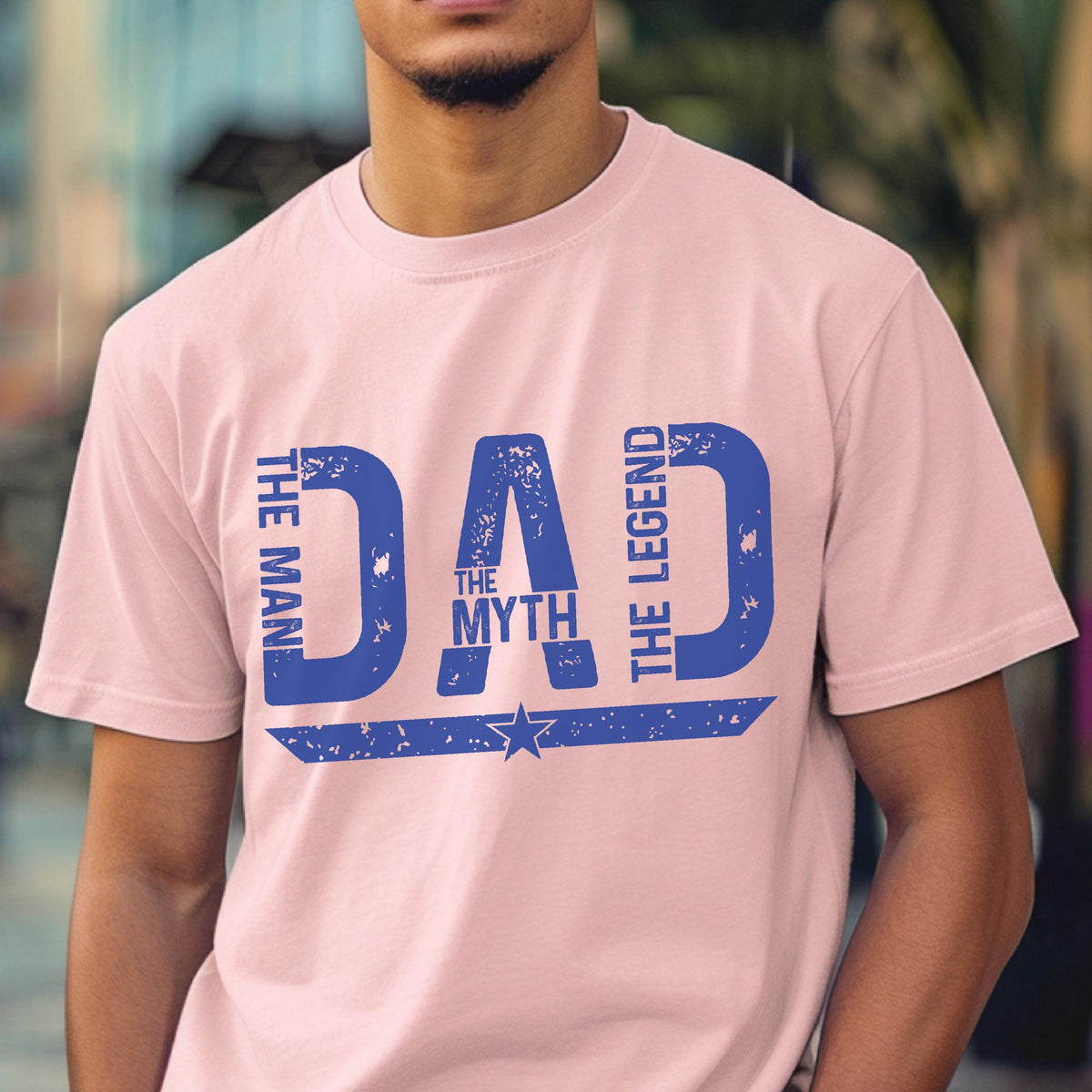 May include: A light pink t-shirt with a blue graphic that says "DAD" with the words "THE MAN", "THE MYTH", and "THE LEGEND". A star is below the word "MYTH".