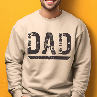 May include: A beige sweatshirt with the text "DAD" in a distressed, dark gray font. The words "THE MAN," "THE MYTH," and "THE LEGEND" are arranged around the word "DAD."