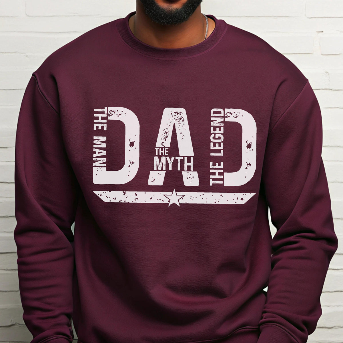 May include: A maroon sweatshirt with the word "DAD" in large white distressed letters. The words "THE MAN", "THE MYTH", and "THE LEGEND" are vertically stacked on either side of "DAD". A white star is centered below the word "DAD".