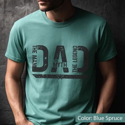 May include: Blue spruce t-shirt with the text "DAD The Myth The Legend" in distressed black lettering. The words "The Man" and "The Legend" flank the sides of the word "DAD". A star graphic is below the word "Myth".