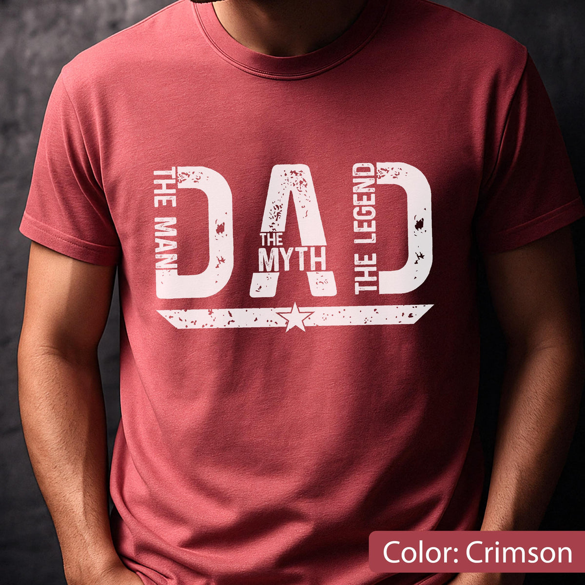 May include: Crimson-colored t-shirt with the text "DAD" in large, distressed white letters. The words "THE MAN," "THE MYTH," and "THE LEGEND" are also printed on the shirt. A star graphic is below the word "MYTH".