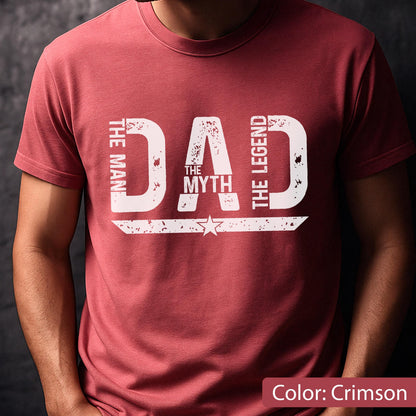 May include: Crimson-colored t-shirt with the text "DAD" in large, distressed white letters. The words "THE MAN," "THE MYTH," and "THE LEGEND" are also printed on the shirt. A star graphic is below the word "MYTH".