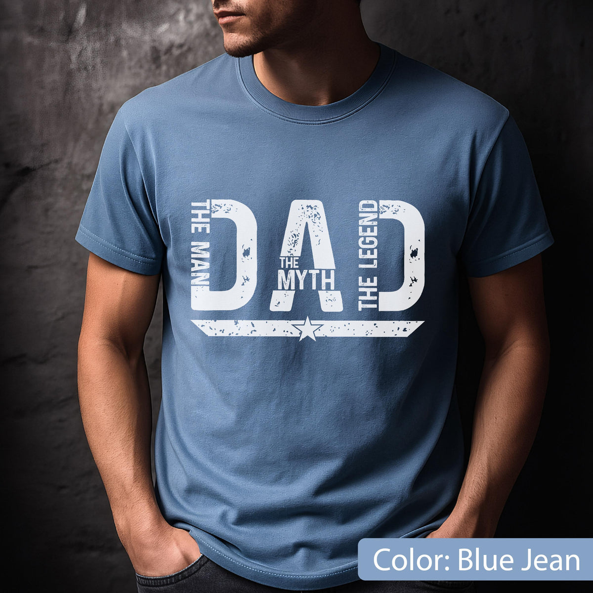 May include: Blue jean-colored t-shirt with the text "DAD" in large, distressed white letters. The words "THE MAN", "THE MYTH", and "THE LEGEND" are also printed on the shirt. A star graphic is below the word "DAD".