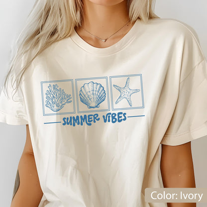 May include: Ivory-colored t-shirt featuring three blue square illustrations of coral, a seashell, and a starfish. Below the illustrations, the words "SUMMER VIBES" are printed in blue.