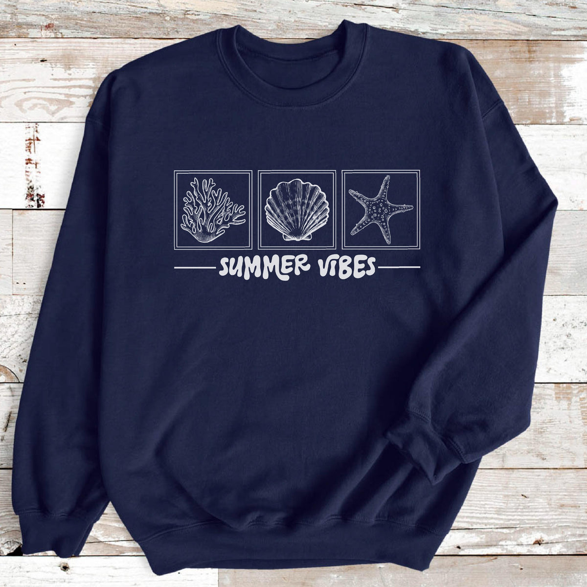 May include: Navy blue sweatshirt with a white graphic of coral, a seashell, and a starfish in square frames. The words "SUMMER VIBES" are printed below the images in white.