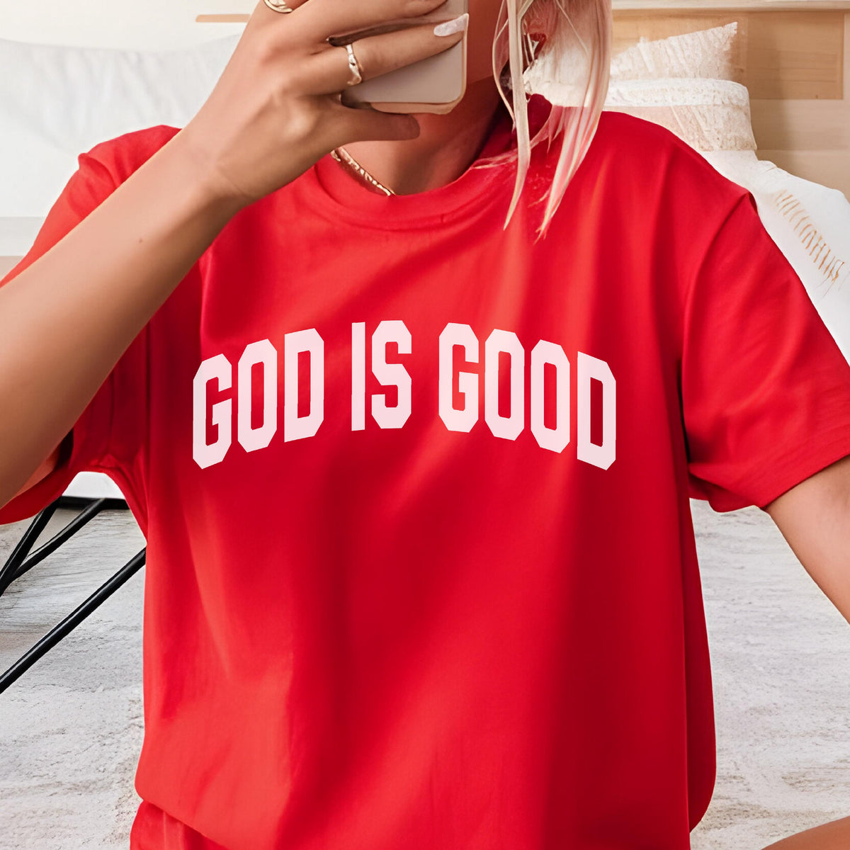 May include: A red t-shirt with the white text "GOD IS GOOD" in a bold, sans-serif font. The short-sleeved shirt is made of a soft material and is suitable for casual wear. The shirt is a solid red color.