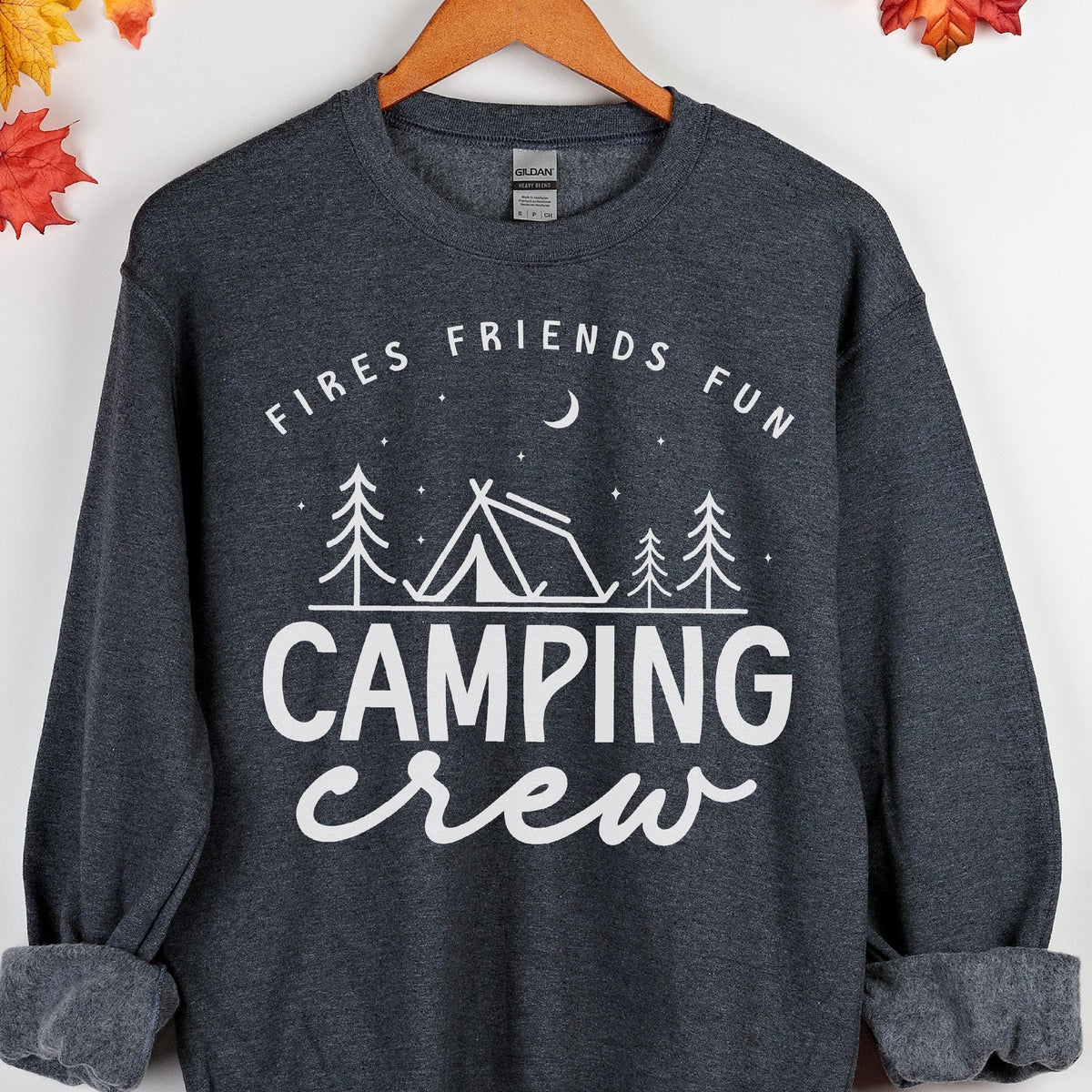 May include: Dark gray sweatshirt with white text that reads "Fires Friends Fun" above a tent and trees graphic, with "Camping Crew" below. The sweatshirt is on a wooden hanger.