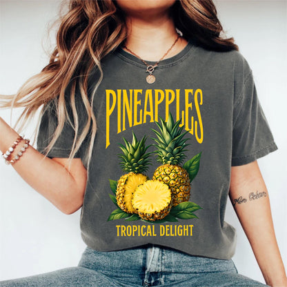 May include: Dark gray t-shirt with a yellow graphic that says "PINEAPPLES" above a pineapple illustration. The illustration includes two whole pineapples and a sliced pineapple, with the text "TROPICAL DELIGHT" below.