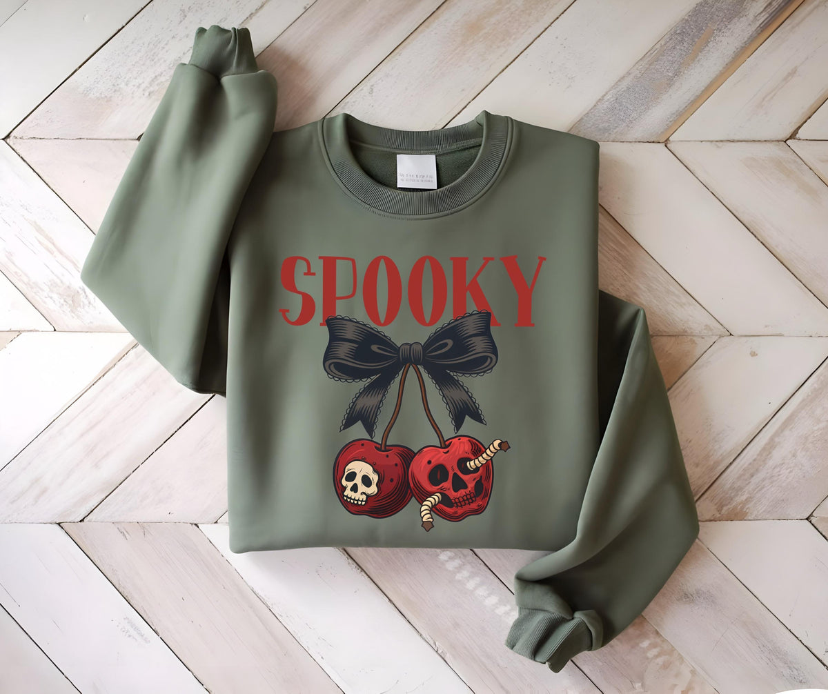 May include: An olive green sweatshirt with the word "SPOOKY" in red letters. Below the text is a black bow and two cherries with skull faces and worms. The sweatshirt has long sleeves and a crew neck.