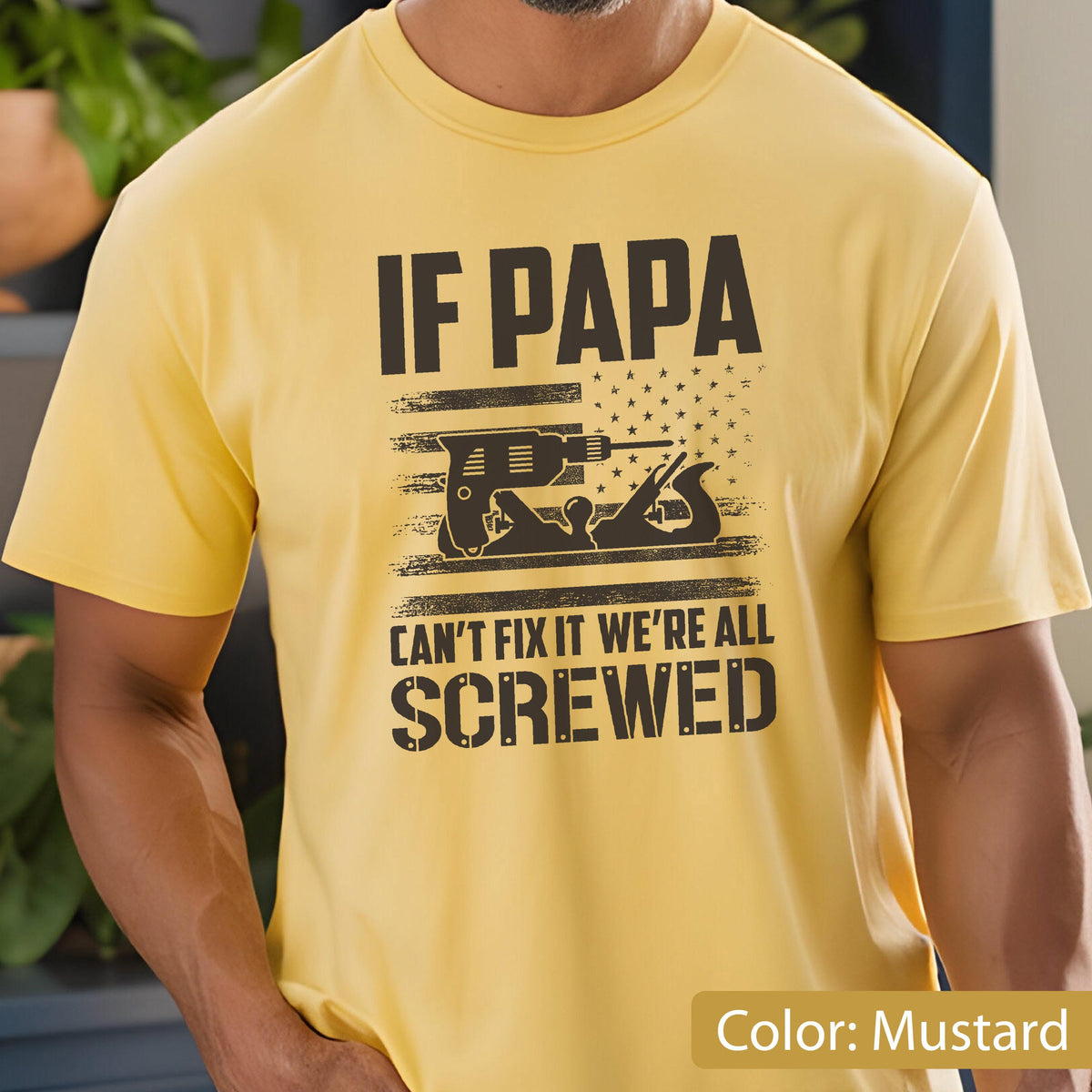 May include: Mustard yellow t-shirt with the text "IF PAPA CAN'T FIX IT WE'RE ALL SCREWED." The graphic includes a drill and a hand plane, with an American flag design. The shirt is short-sleeved.