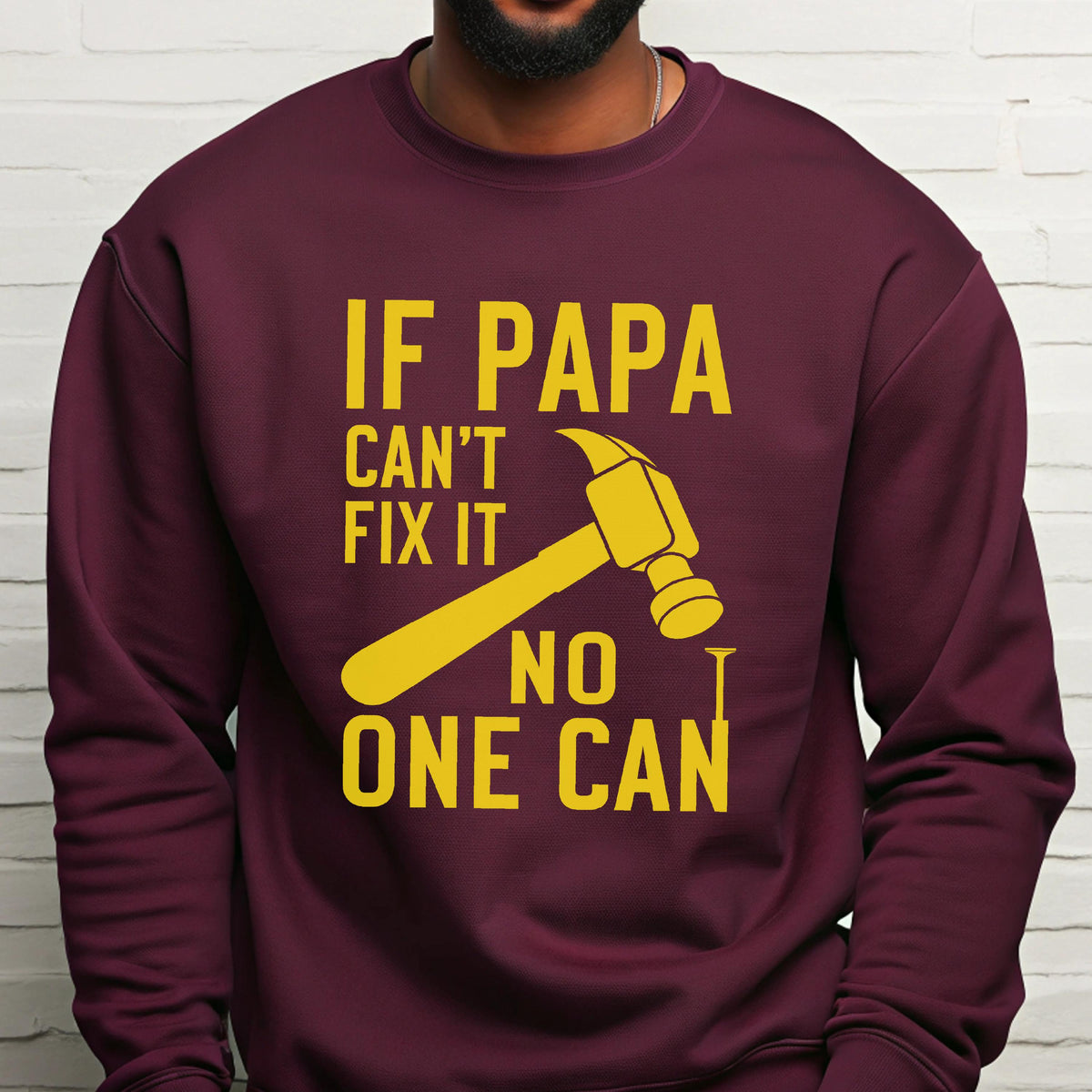 May include: Burgundy sweatshirt with a yellow graphic of a hammer and the text "IF PAPA CAN'T FIX IT NO ONE CAN". The design is centered on the front of the long-sleeved crew neck shirt.