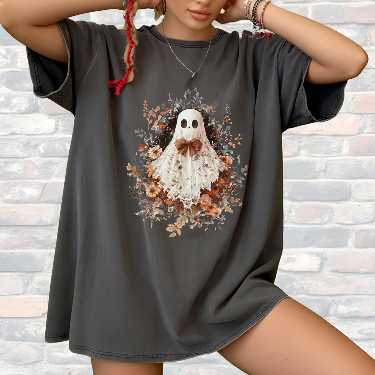 May include: Dark gray t-shirt featuring a floral ghost design. The ghost is white with a brown bow tie, surrounded by a wreath of flowers in shades of orange, yellow, and green. The shirt has short sleeves and a relaxed fit.