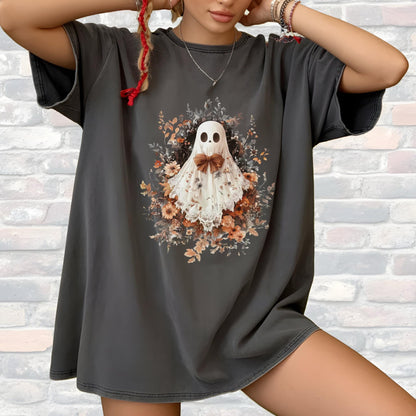 May include: Dark gray t-shirt featuring a floral ghost design. The ghost is white with a brown bow tie, surrounded by a wreath of flowers in shades of orange, yellow, and green. The shirt has short sleeves and a relaxed fit.