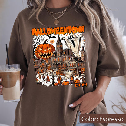 May include: An espresso-colored t-shirt featuring a graphic print with the text HALLOWEENTOWN EST. 1998. The design displays a large jack-o'-lantern, a haunted mansion, ghosts, and various figures in a town setting with orange and black accents.