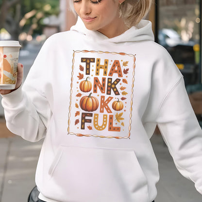 May include: White hooded sweatshirt with a "THANKFUL" graphic in fall colors. The design includes pumpkins and autumn leaves. The sweatshirt has a front pocket and a drawstring hood. A person is holding a coffee cup.