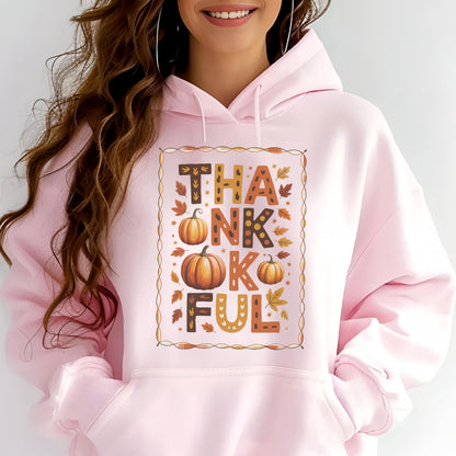 May include: A light pink hoodie with a graphic that says "THANKFUL" in brown and orange letters. The design includes pumpkins and fall leaves. The hoodie has a drawstring hood and a front pocket.
