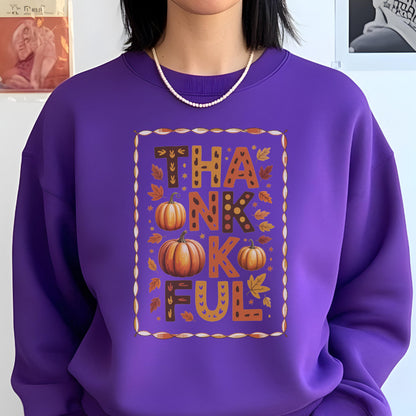 May include: A purple sweatshirt with the word "THANKFUL" in a fall-themed design. The design includes pumpkins and autumn leaves in shades of orange, brown, and yellow. The sweatshirt is a solid purple color.