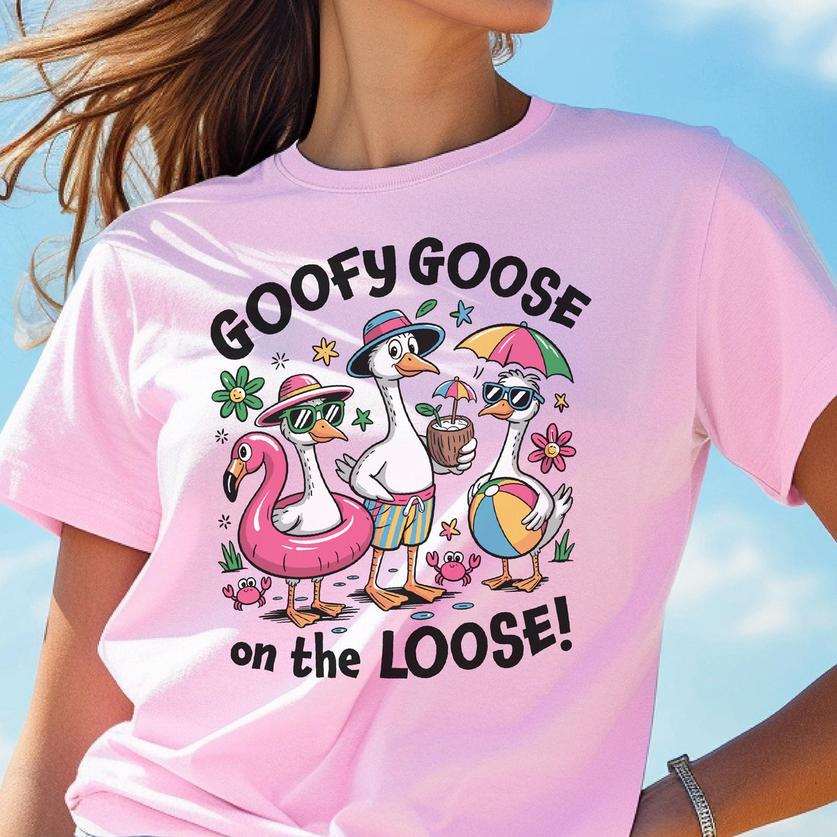 May include: Pink t-shirt with the text "GOOFY GOOSE on the LOOSE!" and a graphic of three cartoon geese at the beach. One goose wears a flamingo floatie, another holds a coconut drink, and the third holds a beach ball.