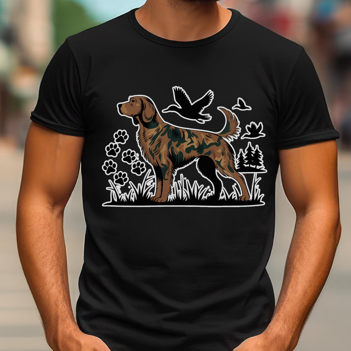 May include: A black short-sleeved t-shirt featuring a graphic print of a brown dog with a camouflage pattern. The design includes white line art of paw prints, flying ducks, and pine trees set against a grassy landscape background.