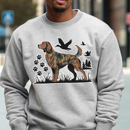May include: A light gray sweatshirt featuring a brown and black dog illustration with a camouflage pattern. The design includes paw prints, flying birds, and trees. The sweatshirt is made of a soft material.