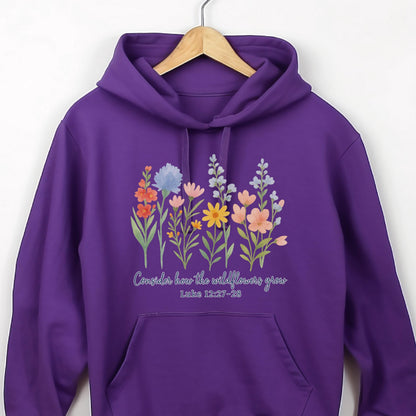 May include: A purple hoodie featuring a floral design with various wildflowers in shades of orange, blue, pink, and yellow. The text "Consider how the wildflowers grow" and Luke 12:27-28 are printed below the flowers.
