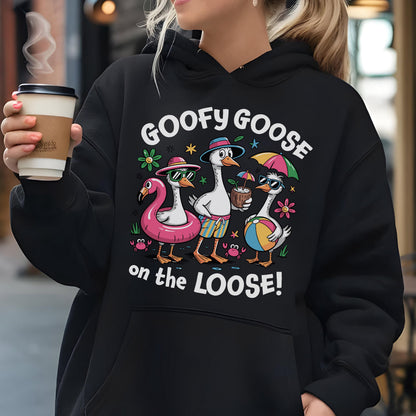 May include: Black hoodie featuring a cartoon design of three geese in sunglasses and beach attire. The text "GOOFY GOOSE on the LOOSE!" is printed above the geese. The geese are wearing a flamingo float, holding a coconut drink, and a beach ball.