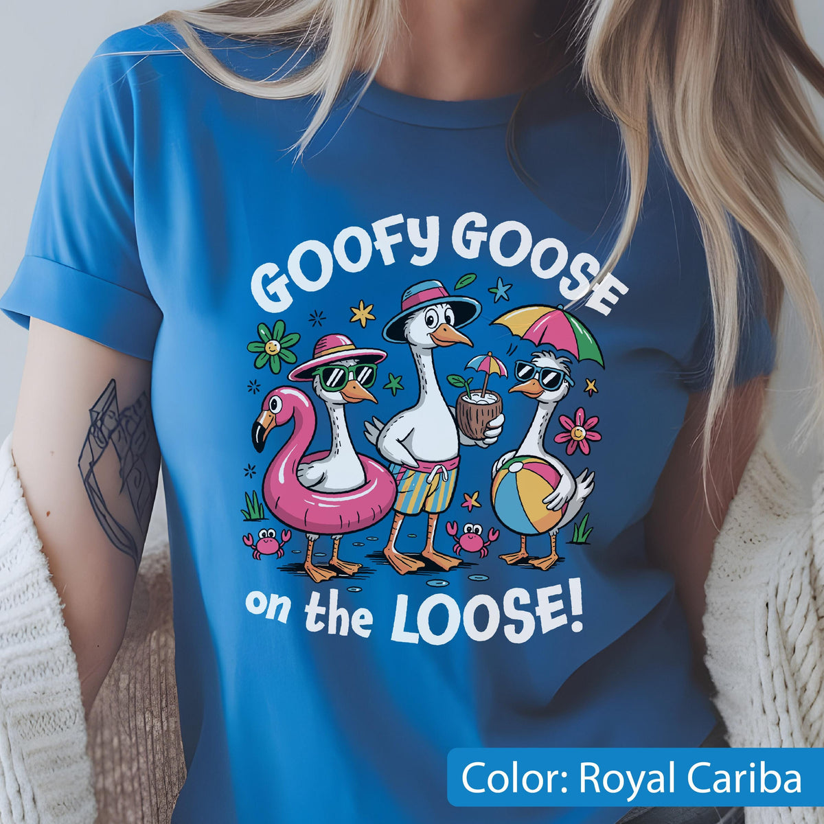 May include: A royal blue t-shirt featuring a graphic of three geese on vacation. The text reads GOOFY GOOSE on the LOOSE! The geese wear sunglasses, hats, and swim trunks, while holding a coconut drink, a beach ball, and a pink flamingo floatie.