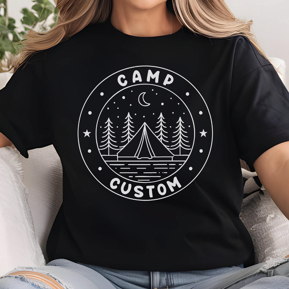 May include: A black short-sleeved t-shirt featuring a white circular graphic print. The design includes a tent, pine trees, a crescent moon, and stars, with the text CAMP at the top and CUSTOM at the bottom of the circular border.