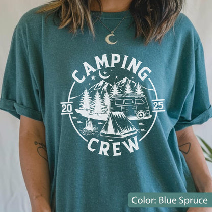 May include: A blue spruce t-shirt featuring a white graphic of a camping scene with a van, a tent, a campfire, mountains, and trees. The text reads "CAMPING CREW" in a circular design with the numbers "20" and "25" on the left and right sides.