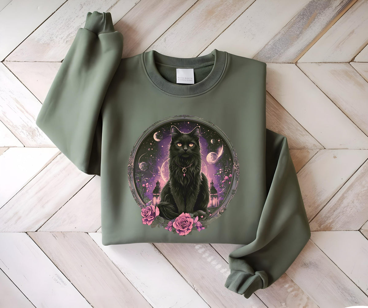 May include: Olive green sweatshirt featuring a detailed illustration of a black cat with glowing eyes, set within a circular frame. The cat is surrounded by a celestial background with pink roses at the base. The sweatshirt has long sleeves.