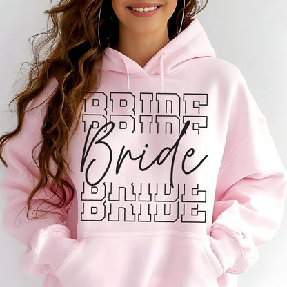 May include: A light pink hooded sweatshirt featuring a front graphic with the word Bride written in a large black cursive script, layered over the word BRIDE repeated four times in a bold, black, outlined block font across the chest area.
