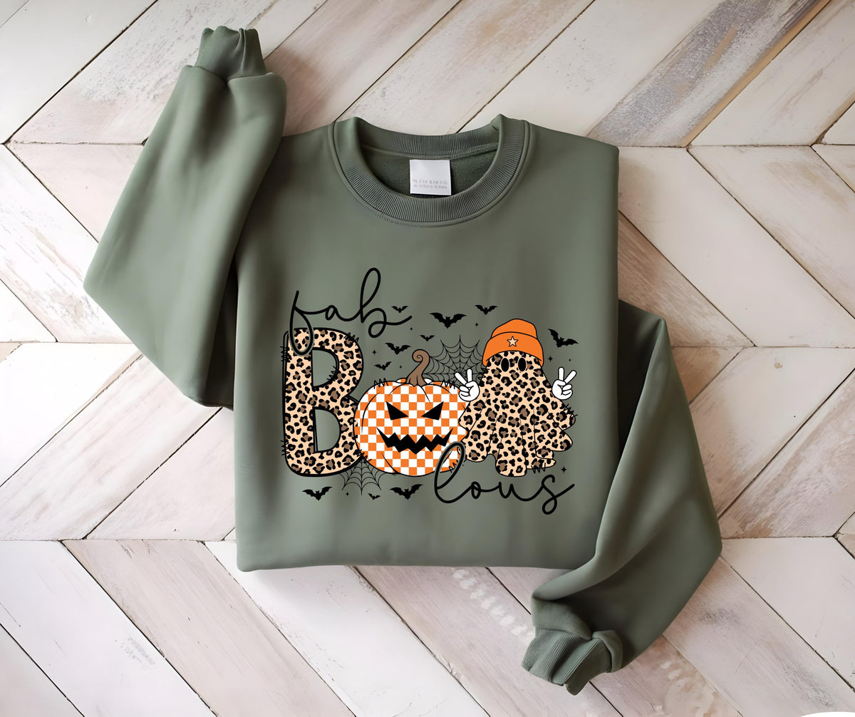 May include: An olive green crewneck sweatshirt featuring a graphic print with the text "fab-lous" and "BOO". The design includes a leopard print letter B, a checkered orange and white pumpkin, a spider web, bats, and a leopard print ghost.