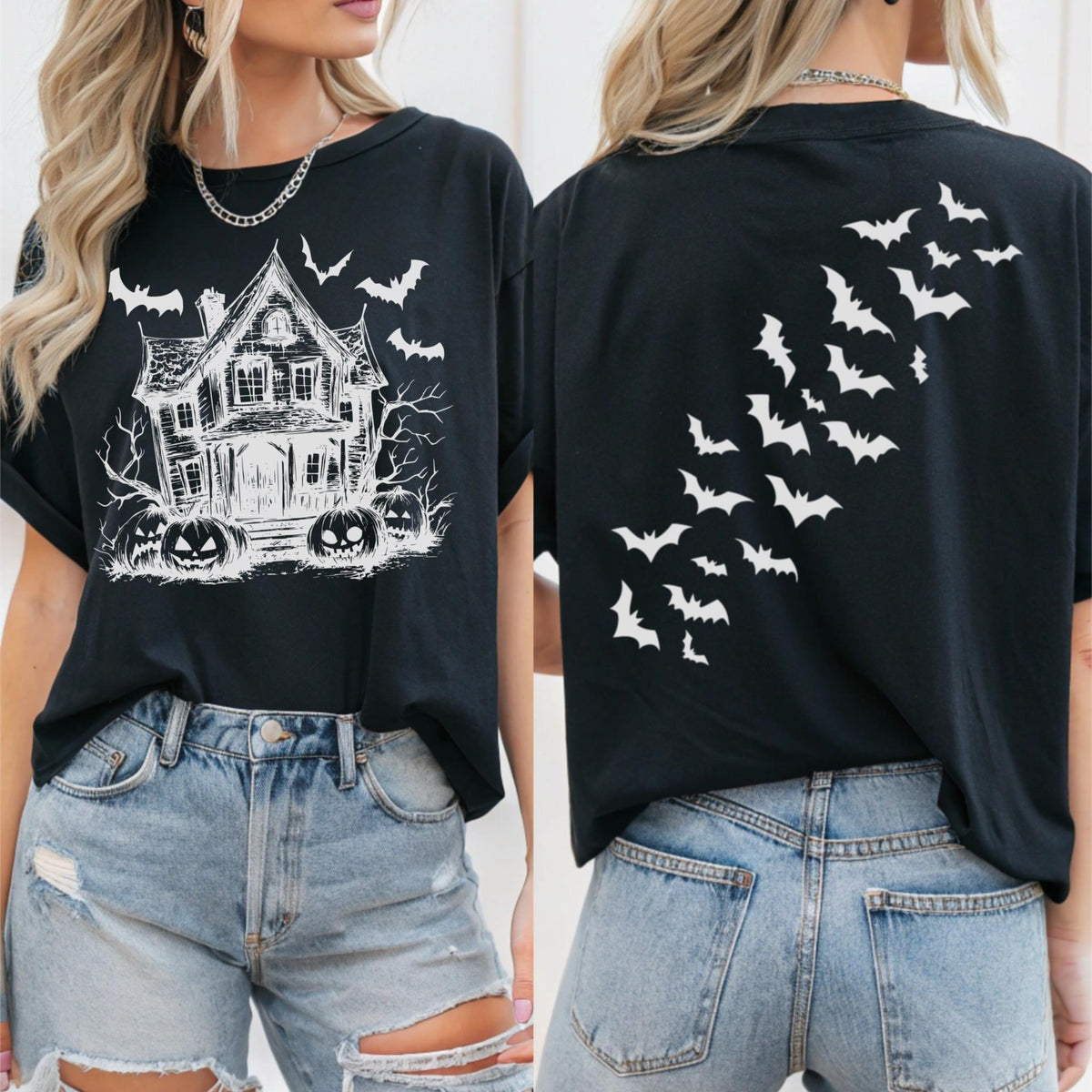 May include: Black t-shirt featuring a white graphic of a haunted house, bats, and jack-o'-lanterns on the front. The back of the shirt displays a flock of white bats. The shirt is a casual, short-sleeved style, perfect for Halloween.