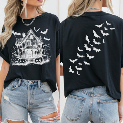 May include: Black t-shirt featuring a white graphic of a haunted house, bats, and jack-o'-lanterns on the front. The back of the shirt displays a flock of white bats. The shirt is a casual, short-sleeved style, perfect for Halloween.